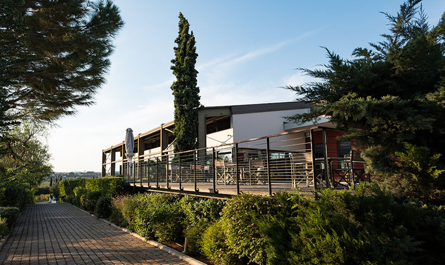 cobblestone alley front of one side of the Domaine Papagiannakos winery building surrounded by trees